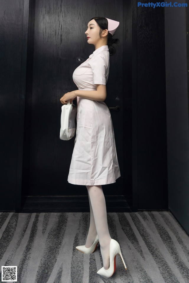 A woman in a white dress and white shoes standing in front of a door.