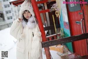 A woman sitting on a bench in the snow wearing a hat.