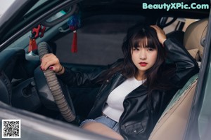 a woman sitting on top of a bench next to a car