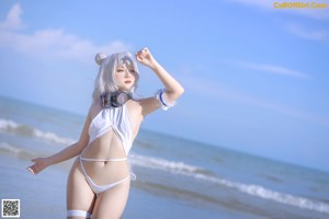A woman in a white bikini standing on the beach.