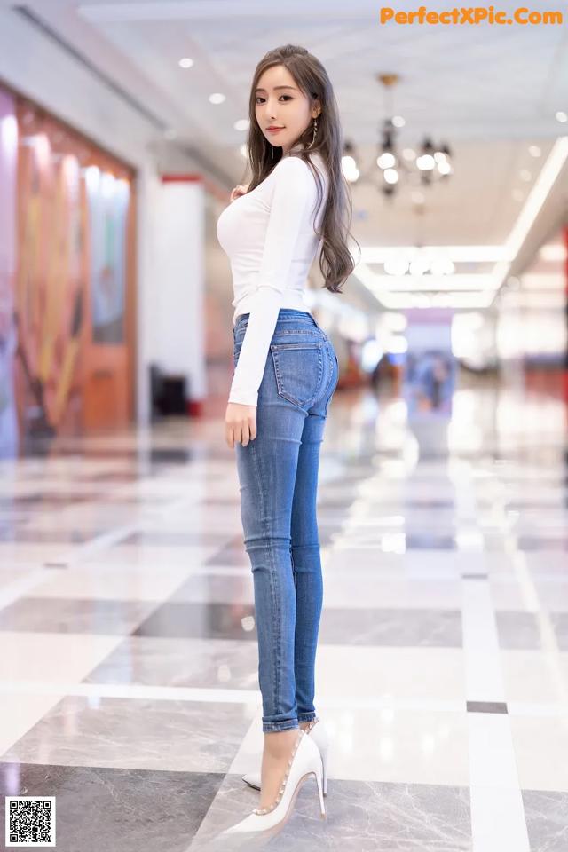 A woman in a white top and blue jeans posing for a picture.
