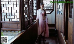 A woman in a pink dress sitting on a bench.
