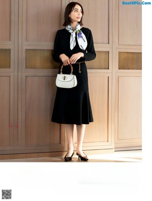 A woman in a black and white dress talking on a cell phone.
