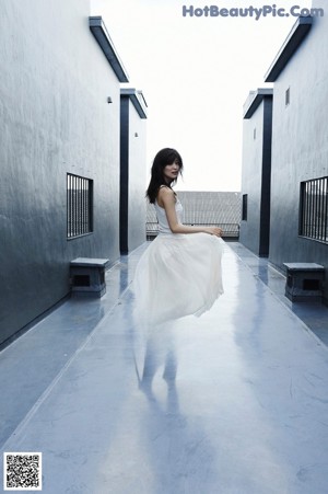 A woman in a white tank top and a white skirt.