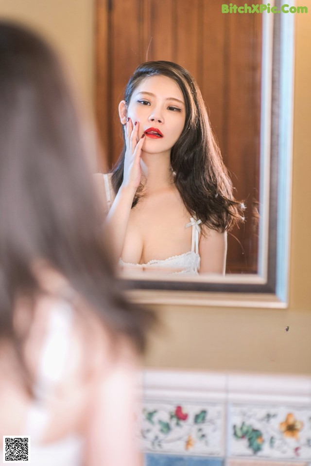 A woman is looking at herself in the mirror.