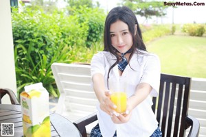 A woman sitting on a bench holding a glass of orange juice.