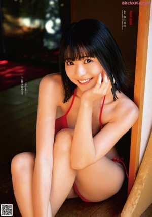 A woman in a bikini sitting on a wooden floor.