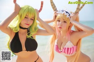 Two women in bikinis are posing for a picture on the beach.