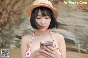 A woman in a bikini and a straw hat posing for a picture.