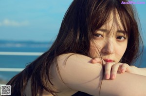 A woman with long brown hair looking out over the ocean.