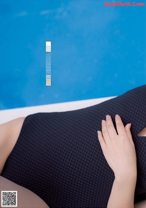 A woman in a blue bikini leaning against a wall.