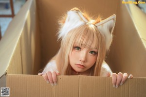 A naked woman in a box with a cat ears on her head.