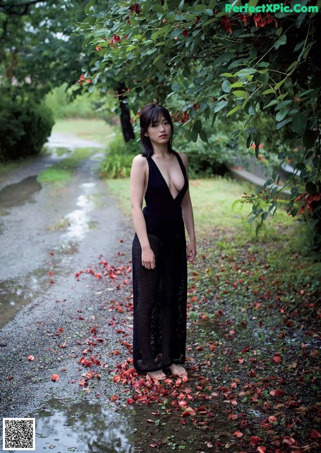 A woman in a black dress standing in a puddle of water.