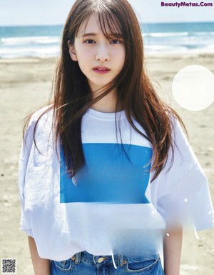 A woman standing on a beach next to the ocean.