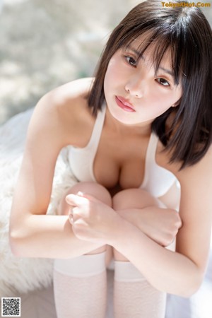 A woman in a white bikini laying on a bed.