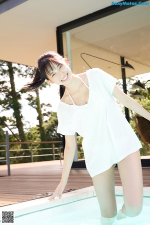 A woman in a black bikini sitting on top of a white rug.