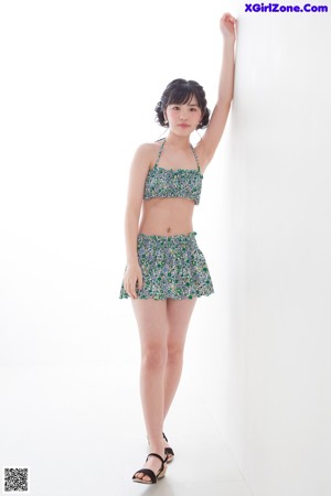 A woman in a bikini top and skirt posing for a picture.