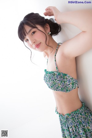 A woman in a bikini top and skirt posing for a picture.