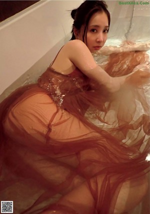 A woman in a red bikini sitting in a bathtub.