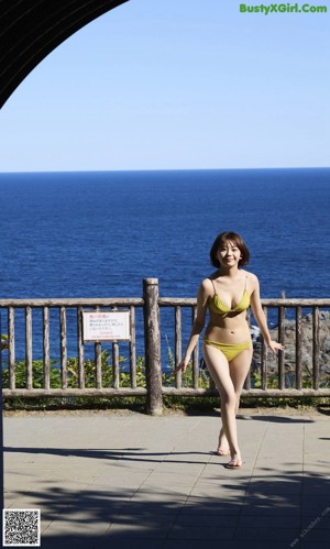 A woman sitting on the ground in front of the ocean.