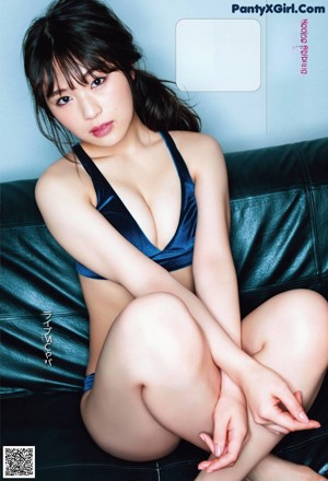 A woman laying on top of a brown couch next to a plant.