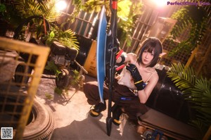 A woman sitting on top of a tire holding a gun.
