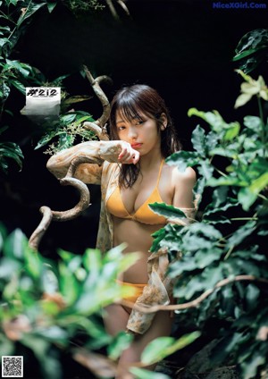 A woman in a red bikini standing in front of a rock.