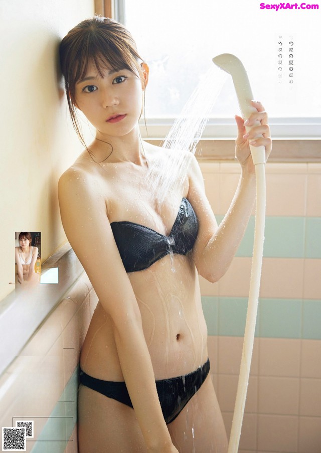 A woman in a black bikini holding a shower head.
