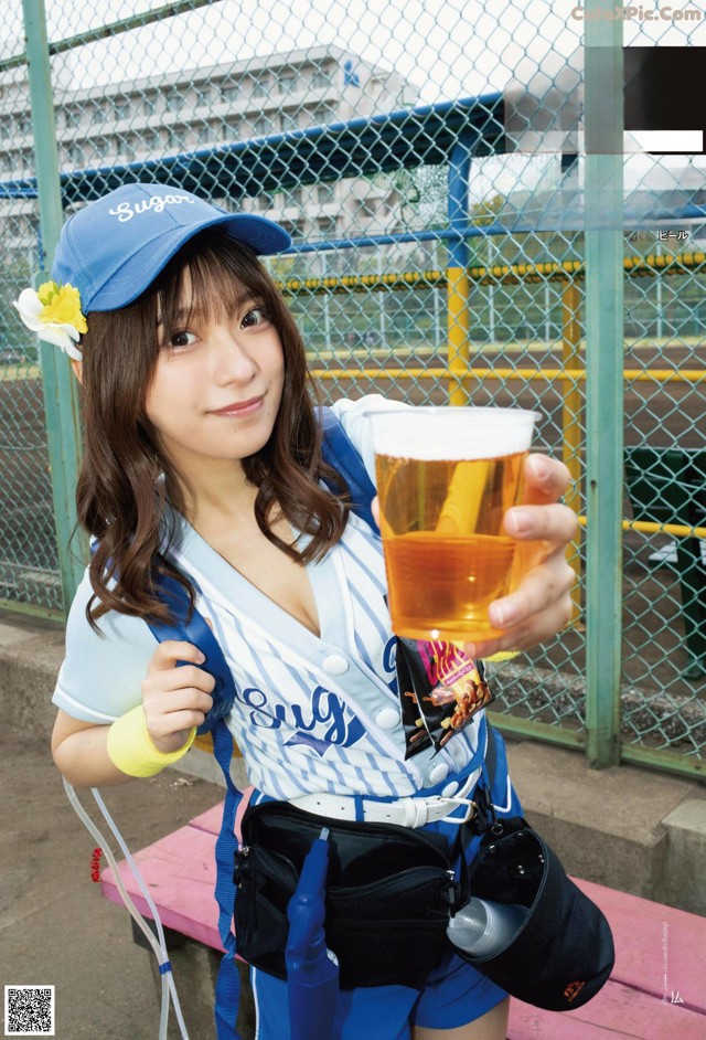 A woman in a baseball uniform holding a glass of beer.