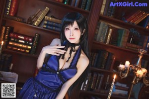 A woman in a blue dress sitting on a chair.