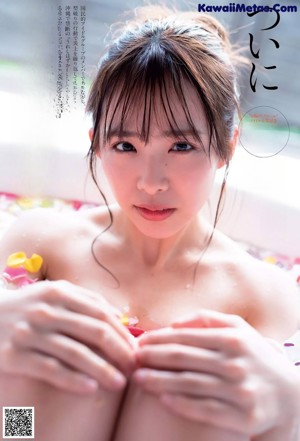 A woman sitting in a bathtub filled with flowers.