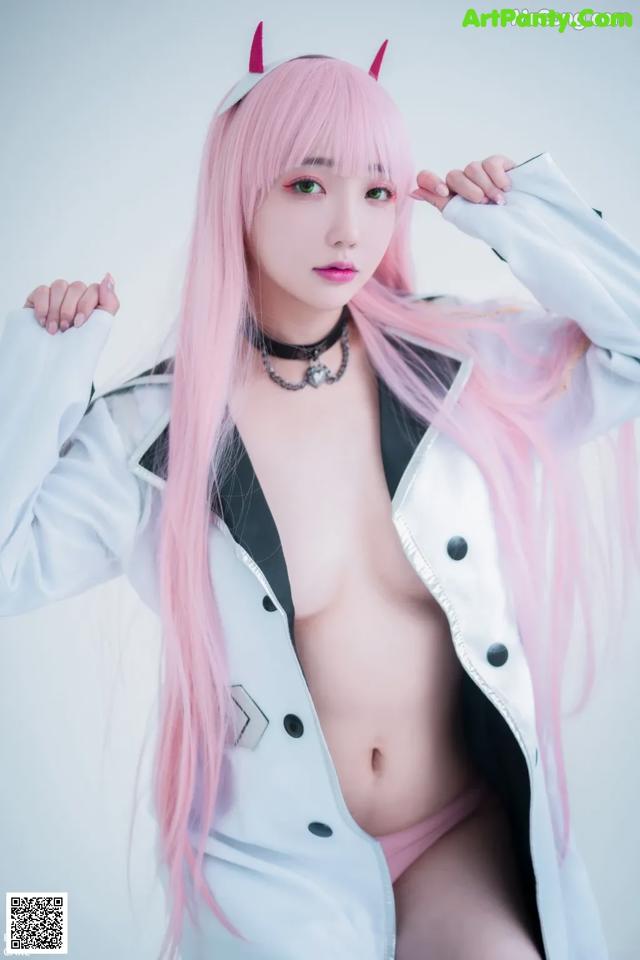 A woman with long pink hair wearing a white coat.