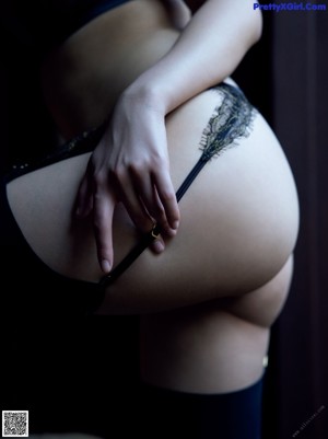 A woman in a sheer black dress posing for a picture.