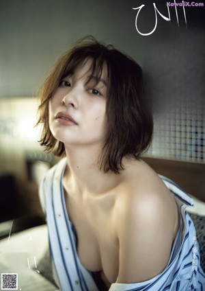 A woman in a blue dress is posing naked on a bed.